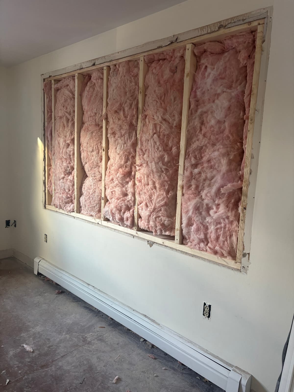 Wall opened to the studs with insulation exposed before repair