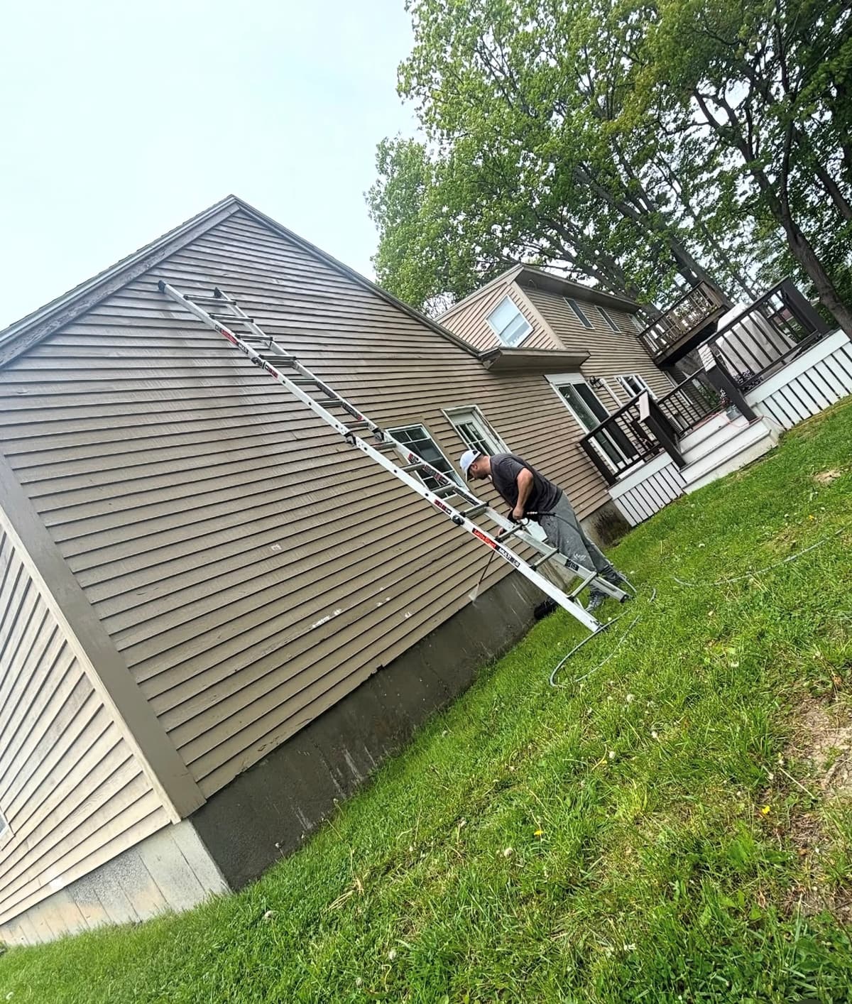 Painter working from a ladder on gable siding